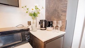 A compact kitchen with a microwave, coffee maker, and two wine glasses on the counter. - Second Floor Suite | Rathmines | WiFi & Comfort (Dublin)