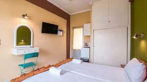Camera d'albergo con un letto, una toeletta con specchio, una televisione e un armadio.
