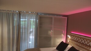 Une chambre d’hôtel avec un lit, des rideaux, une porte-fenêtre coulissante et une tête de lit à motifs.