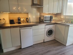 A modern kitchen with a dishwasher, washing machine, microwave, and a toaster.