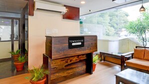 A reception desk labeled 'Townhouse & Company Serviced,' wooden flooring, potted plants, and a sofa. - Deluxepurple Square (Hyderabad)