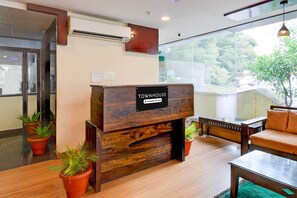 Balcão de recepção com a inscrição 'Townhouse & Company Serviced', soalho de madeira, plantas em vasos e um sofá.