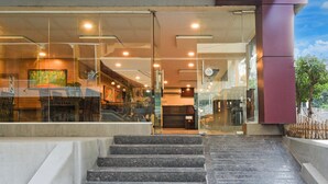 A hotel entrance with a glass facade, a staircase leading up, and a view of the interior. - Deluxepurple Square (Hyderabad)