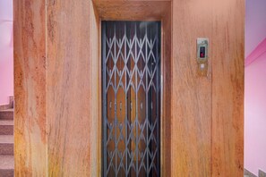 Une porte métallique dotée d’un verrou numérique, un escalier sur la gauche et un mur à la surface texturée.