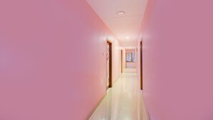 A long, narrow hallway with pink walls and a tiled floor. - Deluxeshanthaa Residency (Hyderabad)