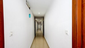 A long, narrow hallway with white walls, wooden doors, and a tiled floor. - Deluxe Amritsar District Court (Amritsar)