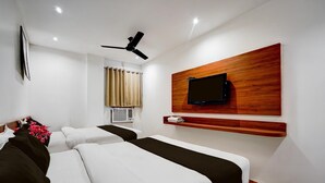 A hotel room with two beds, a ceiling fan, a mounted TV, and an air conditioning unit. - Deluxe Amritsar District Court (Amritsar)