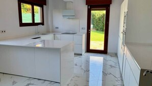 A modern kitchen with a marble countertop, a built-in oven, and a large window. - Ecopausa Somió - Gijón (Gijón)