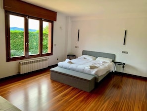 A bedroom with a bed, a bench, a radiator, and a window with a view.