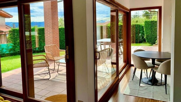 A modern interior with large sliding glass doors leading to an outdoor patio area. - Ecopausa Somió - Gijón (Gijón)