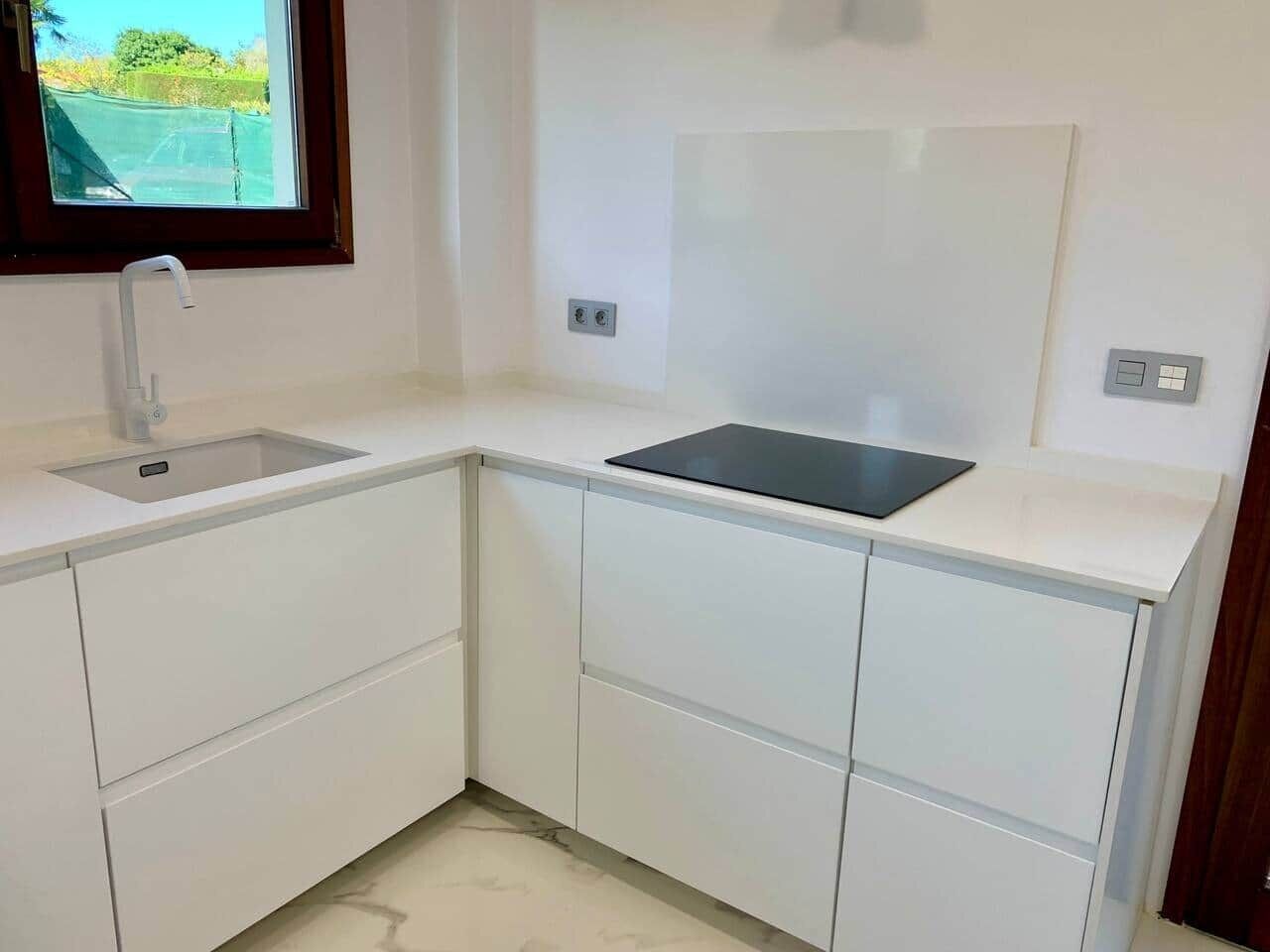 A kitchen with white cabinetry, a black countertop, a window, and a door.