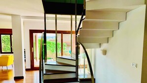 A modern interior with a spiral staircase, wooden flooring, and a view through glass doors. - Ecopausa Somió - Gijón (Gijón)