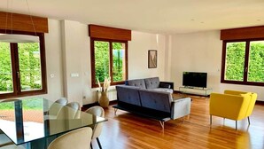 A modern living room with a glass dining table, sofa, and yellow chairs. - Ecopausa Somió - Gijón (Gijón)