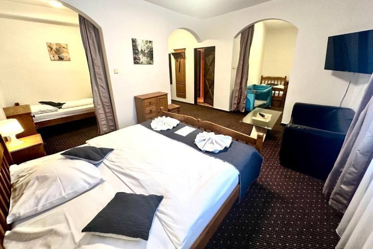 Ein Hotelzimmer mit Bett, Schreibtisch, Stuhl, Fernseher und einem durch einen Bogen sichtbaren Badezimmer.