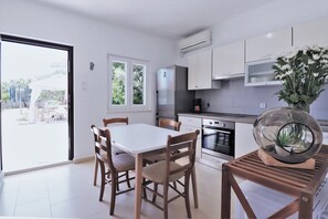 Een moderne keuken met witte kasten, een roestvrijstalen koelkast en een eettafel met stoelen.