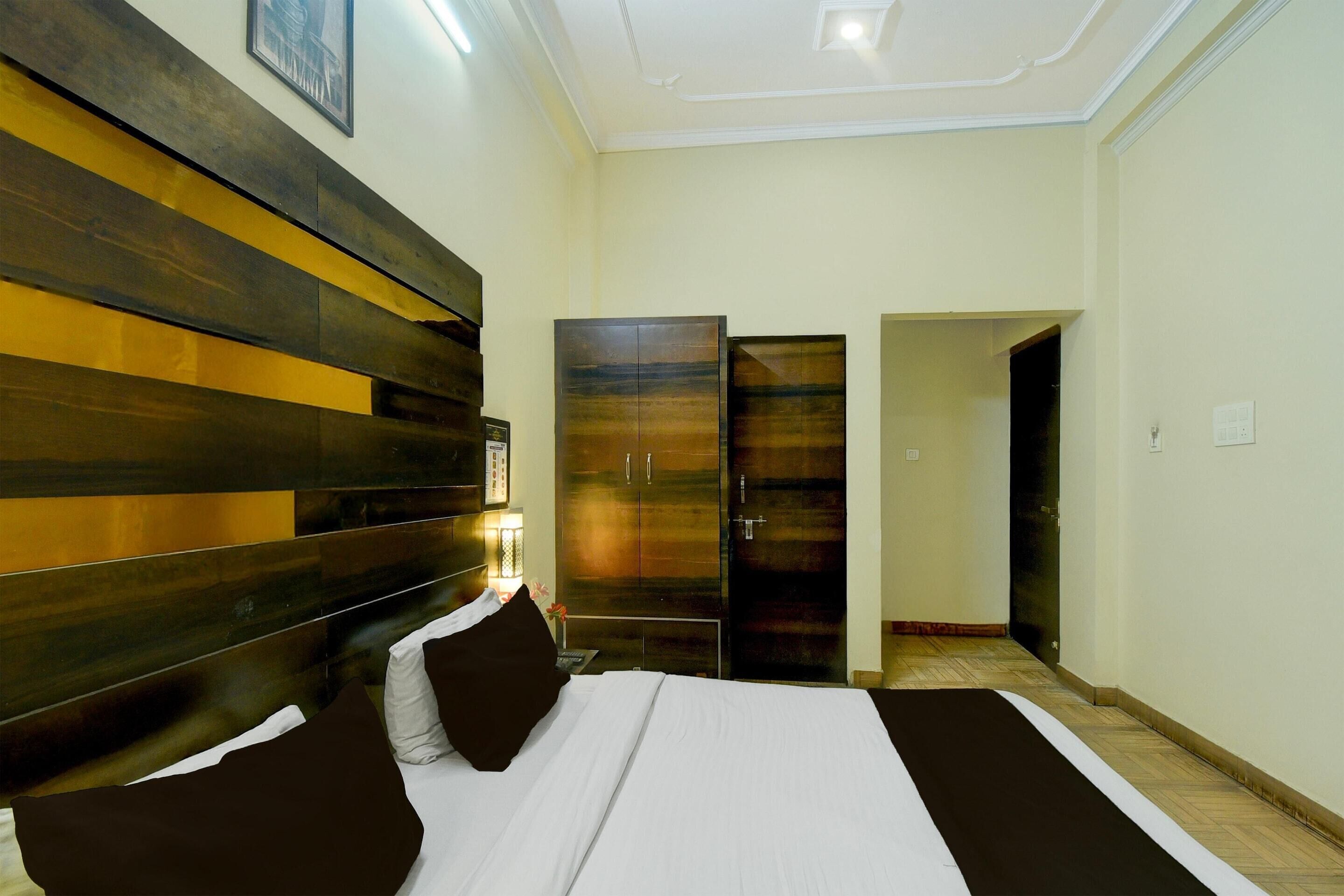 A hotel room with a large bed, a wooden headboard, a wardrobe, and a door leading to another room.