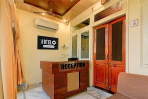 Un taulell de recepció d'hotel amb un cartell, una porta de fusta i un sofà.