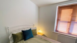 A single bed with a headboard, a bedside table with a lamp, and a window with blinds. - Central Hove near beach & lawns (Brighton and Hove)