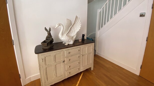 A hallway with a white painted cabinet, a white swan sculpture, and a rabbit sculpture on the wall. - Central Hove near beach & lawns (Brighton and Hove)