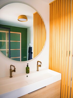 A bathroom with a round mirror, two faucets, a sink, and a wooden panel. - Villa NOOSA - Saltwater pool - Terrace - Seignosse (Seignosse)