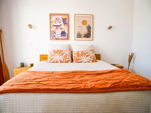 A bed with an orange blanket, white pillows, and two wall-mounted pictures. - Villa NOOSA - Saltwater pool - Terrace - Seignosse (Seignosse)