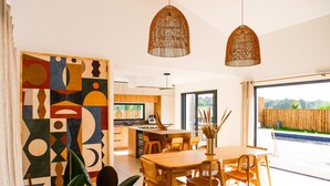 Une cuisine moderne avec des meubles en bois, un coin repas doté d’une table et de chaises en bois, et une grande fenêtre.