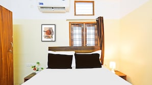 A hotel room with a bed, a window with curtains, a wall-mounted air conditioner, a framed picture, and a nightstand with a lamp. - Deluxe Hotel O Suncity Fort Inn (Hyderabad)