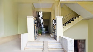 A corridor with a staircase leading to a landing, flanked by two gates. - Deluxe Hotel O Suncity Fort Inn (Hyderabad)
