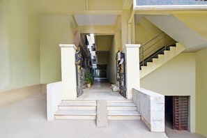 A corridor with a staircase leading to a landing, flanked by two gates. - Deluxe Hotel O Suncity Fort Inn (Hyderabad)