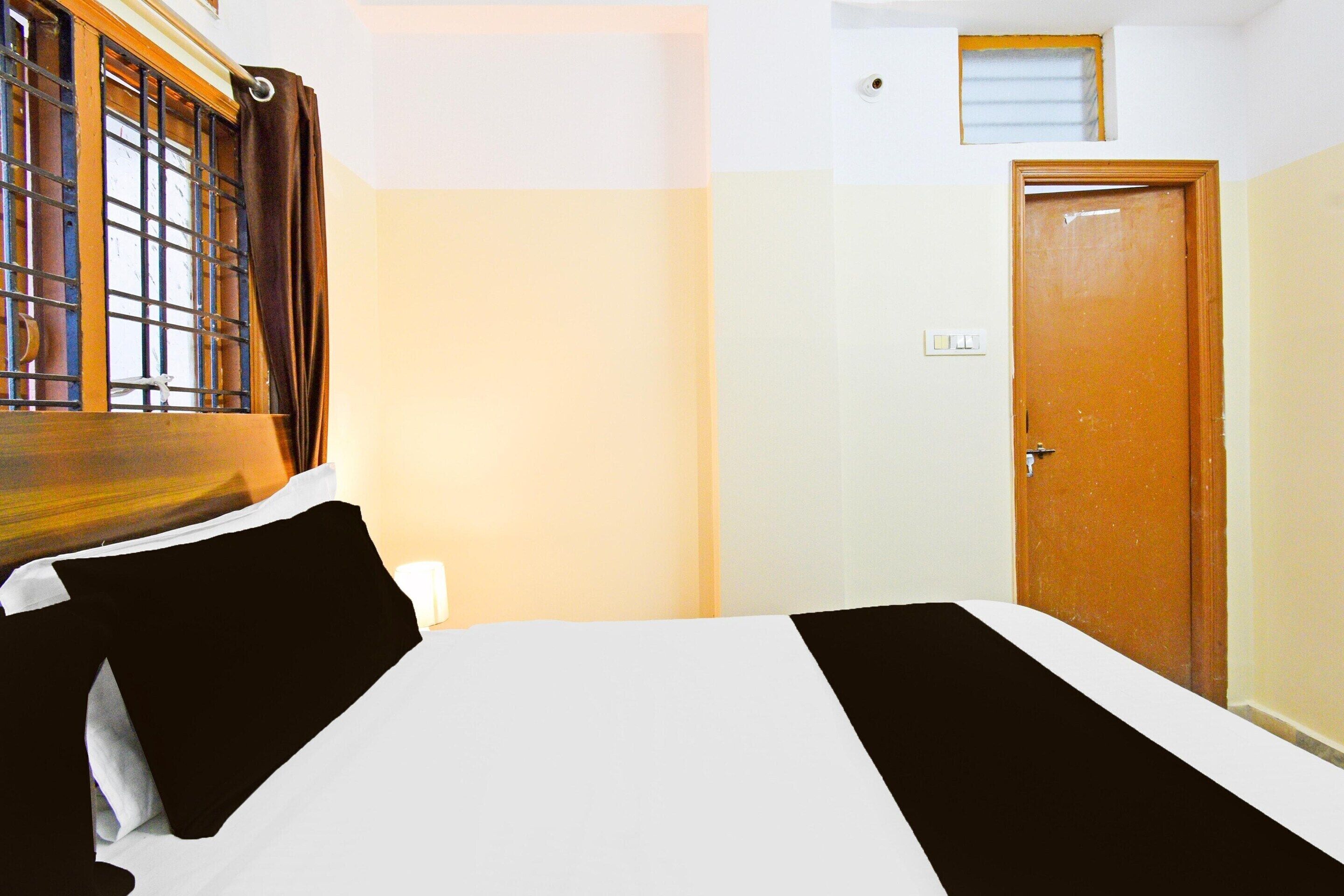 A room with a bed, a wooden door, and a window with bars.