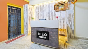 A hotel reception desk with a 'HOTELO' sign, a reception area, a wooden wall, a ceiling fan, and a decorative garland. - Deluxe Hotel O Suncity Fort Inn (Hyderabad)