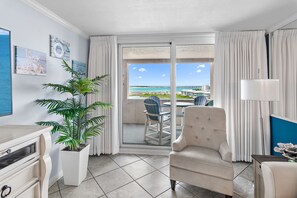 Habitación de hotel con vista al mar, una planta en maceta, una silla, una lámpara y un aparador.