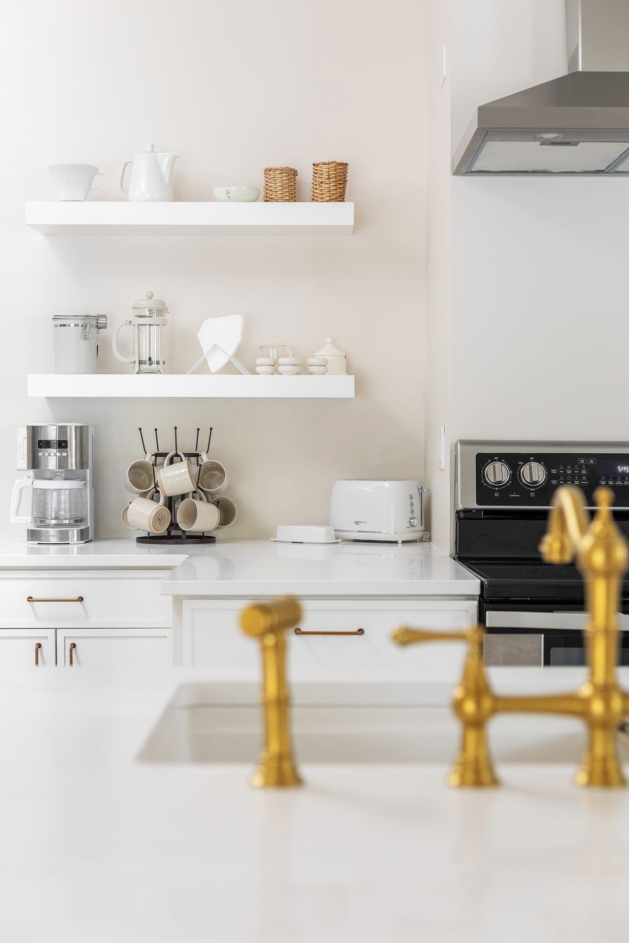 Una cocina moderna con armarios blancos, cafetera, tostadora y estufa.