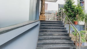 A staircase with metal railings, a blue wall, and a potted plant. - Deluxehotel Surabhi Elite (Hyderabad)