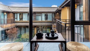 A traditional-style room with a balcony, a table with tea set, and woven baskets. - Aofeng Tangquan Secluded Villa (Dali)