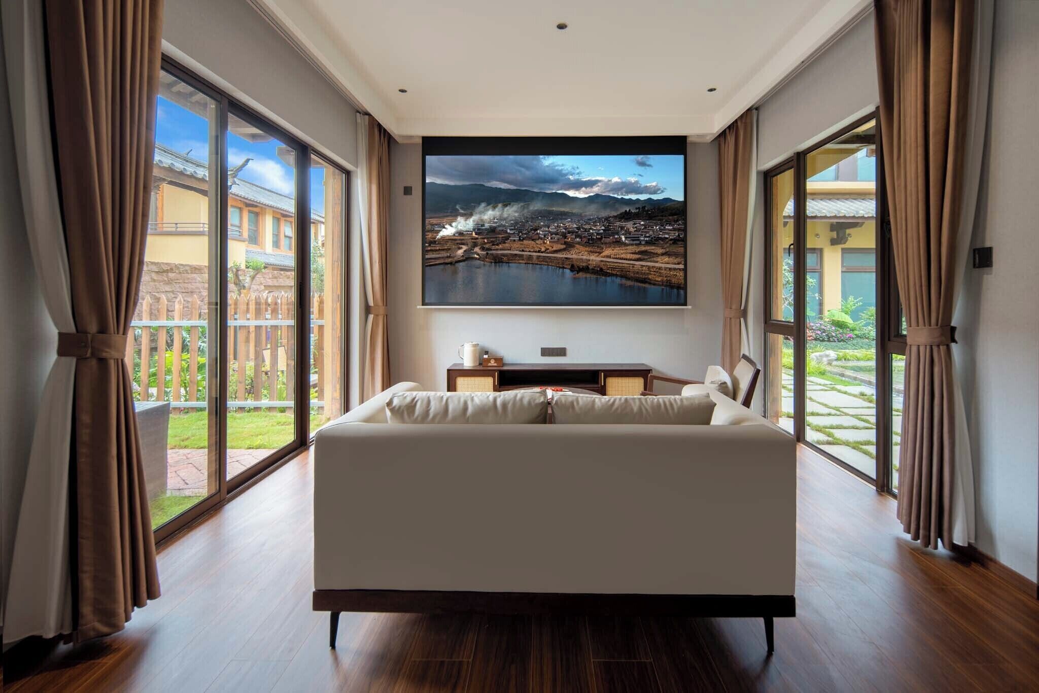 Un dormitorio con una cama grande, un televisor de pantalla plana en la pared y vistas a un patio a través de amplios ventanales.