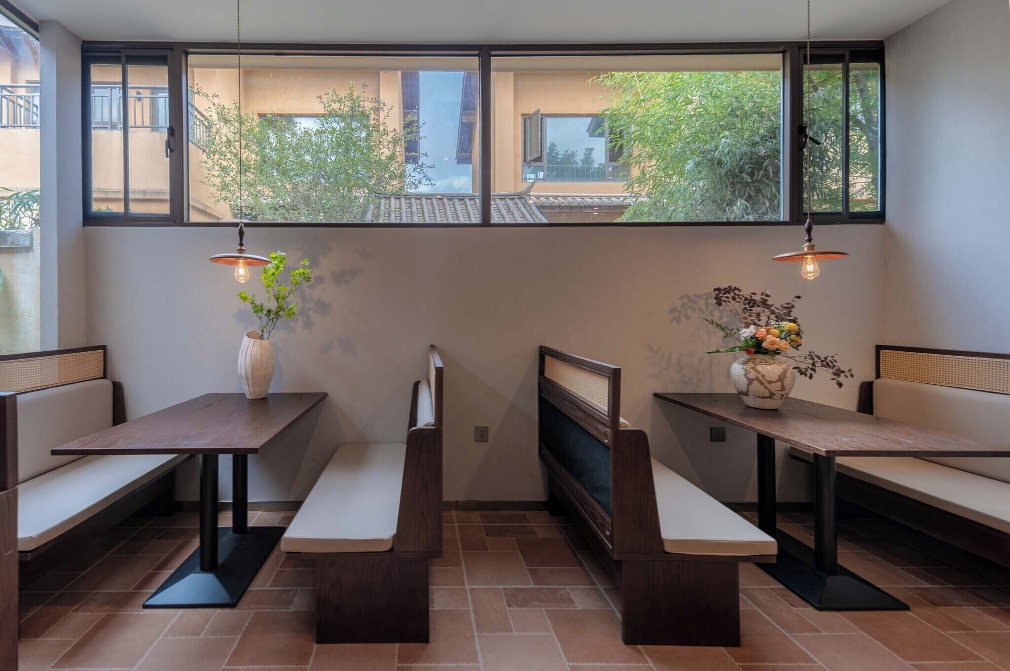 A dining area with wooden benches, a central table, and two hanging lamps.