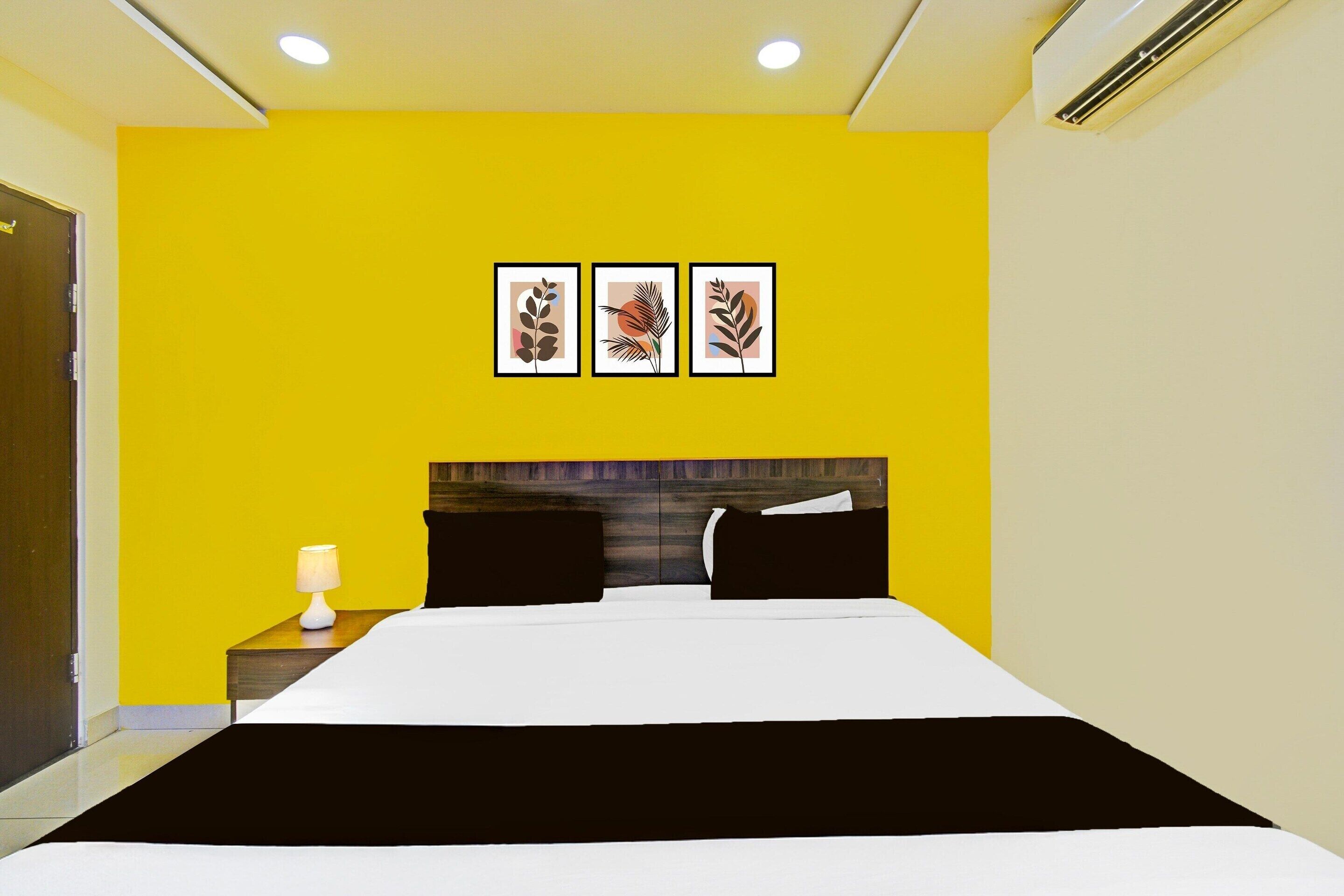 Una camera d'albergo con un letto, un comodino, una lampada e tre quadri appesi al muro.