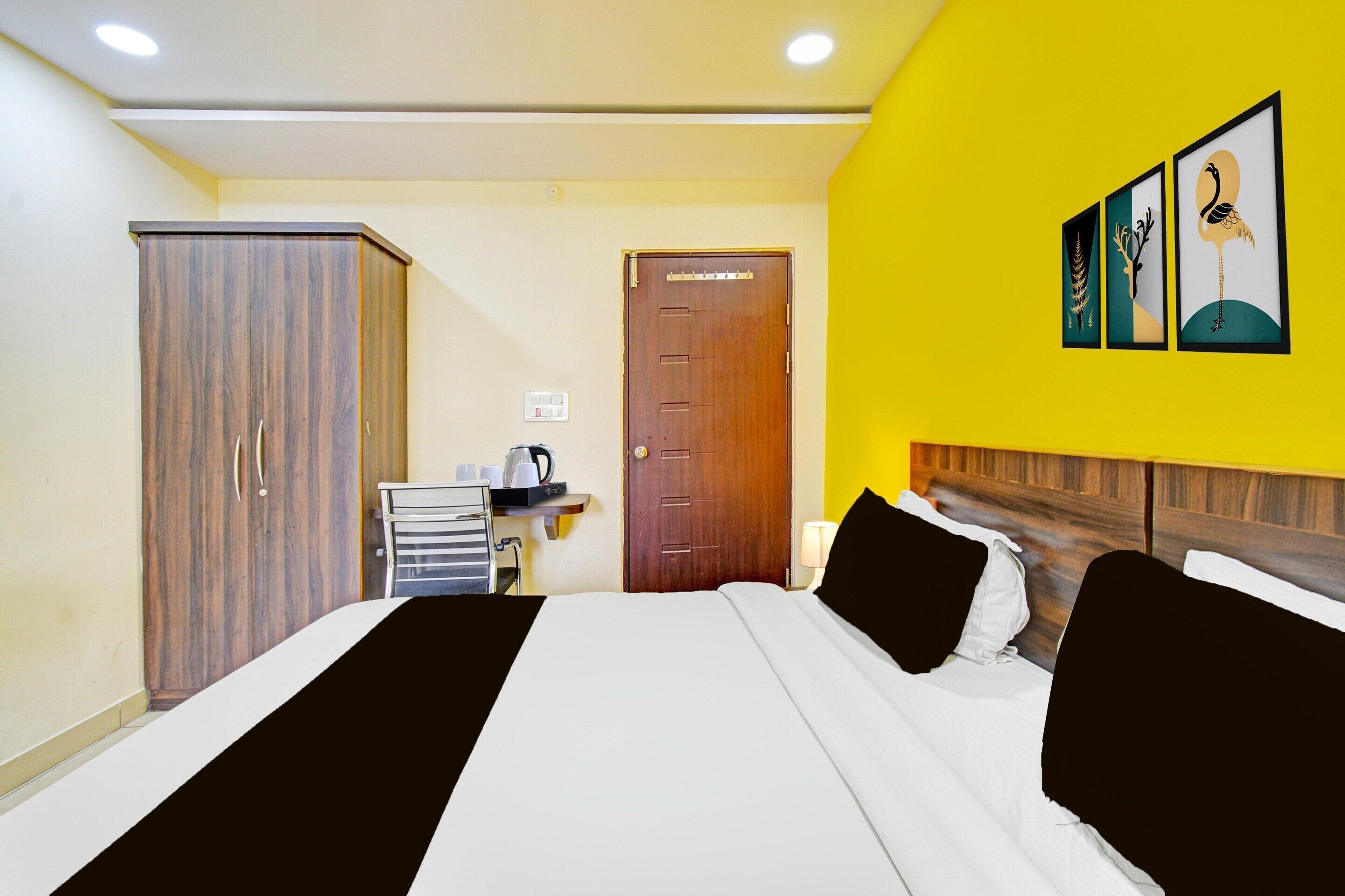 A hotel room with a bed, a wardrobe, a door, and a wall with artwork.