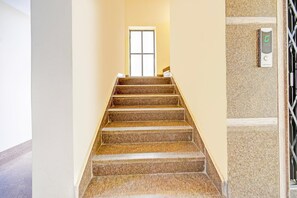 Eine Treppe mit Handlauf, eine Tür oben und ein wandmontiertes Bedienfeld für einen Aufzug.