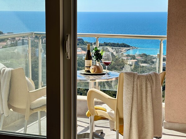 Un balcon avec une table, une bouteille de vin et un verre de vin.