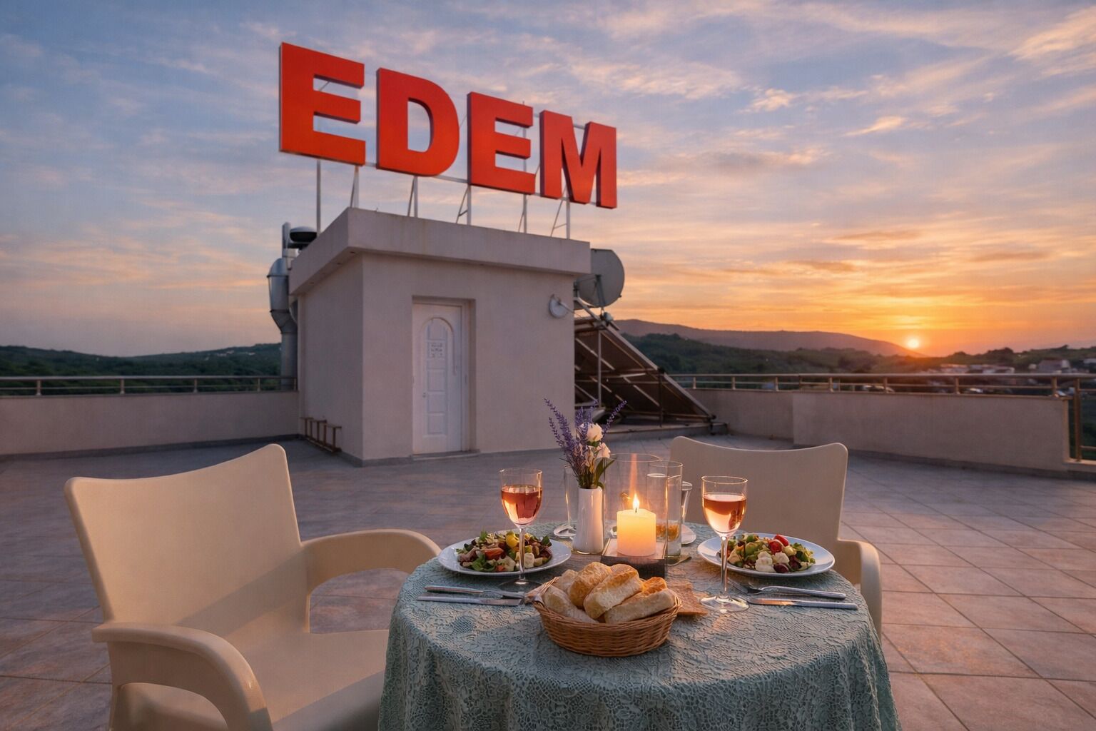 A rooftop dining area with a table set for two, a view of the sunset, and a sign with the word 'EDEM'.