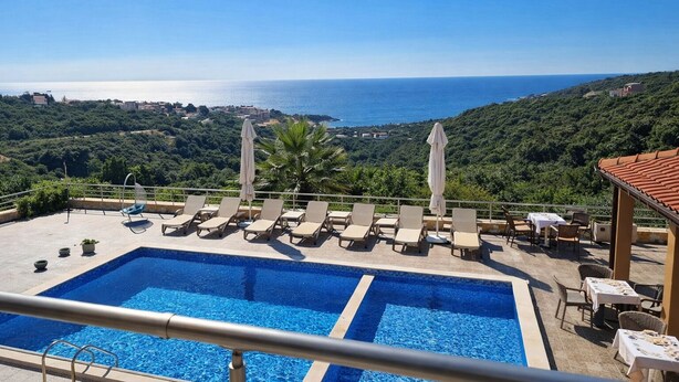 A pool with lounge chairs and umbrellas, overlooking a coastal landscape. - Boutique-Apartments Edem (Utjeha)