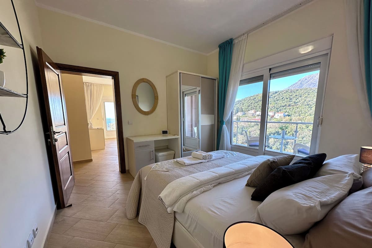 Un dormitorio con cama, mesita de noche y ventana con vistas a un paisaje montañoso.