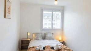Ein Schlafzimmer mit Bett, Nachttischlampen, einem Fenster und einer Pendelleuchte.