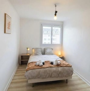 Ein Schlafzimmer mit Bett, Nachttischlampen, einem Fenster und einer Pendelleuchte.