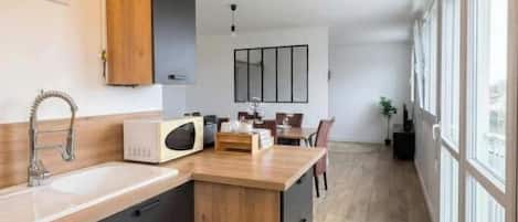 Una cocina moderna con una isla de madera, microondas integrado y un ventanal grande.