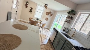 A kitchen with a large island, wooden flooring, and a view of the outdoors.