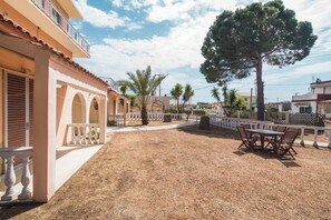 A building with a covered patio, outdoor seating, and a large tree. - Southgate 10 by MPS (Agios Georgios)