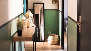 A narrow hallway with a wooden table, a hanging lantern, and a basket on the floor.